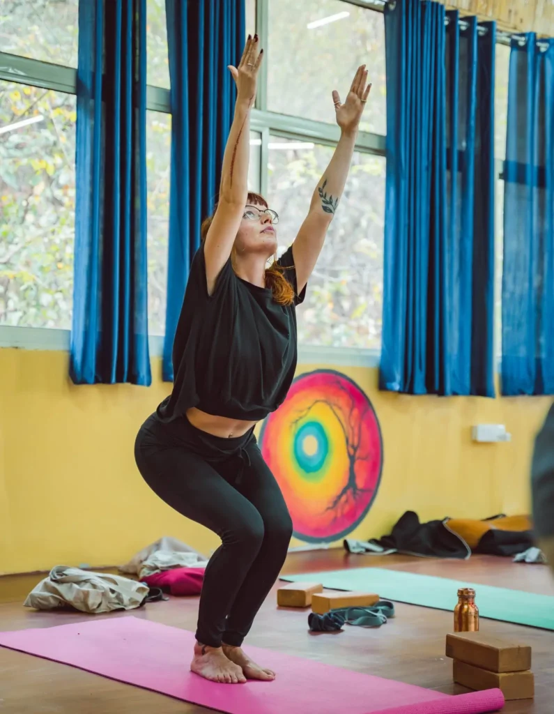 Utkatasana Chair Pose practiced by a woman in a yoga class